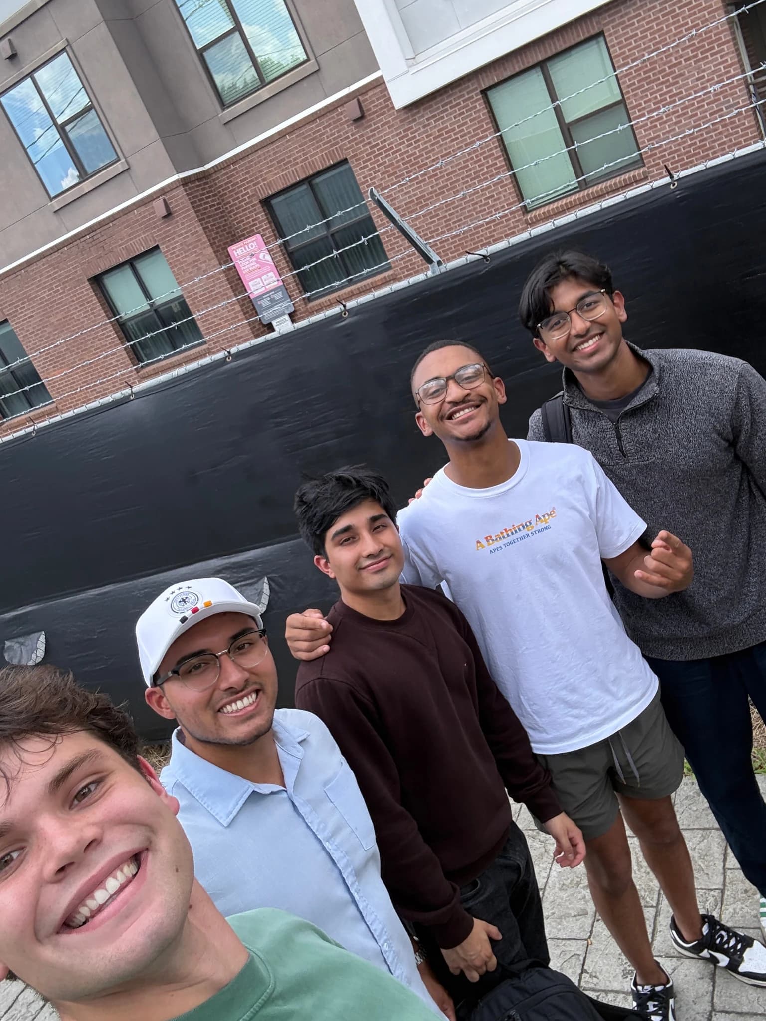 Five people smiling in an outdoor group selfie